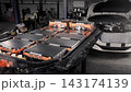 EV car service. Electric vehicle battery pack being serviced or inspected in automotive workshop. Large battery modules and high voltage components. Modern EV power systems. Lithium ion NMC NCA or LFP 143174139