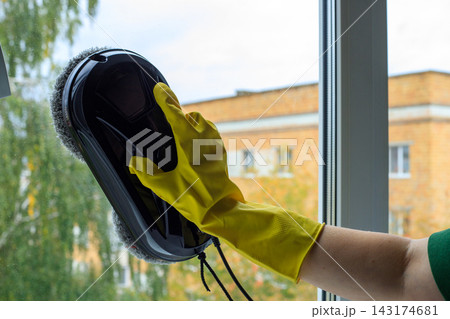 Window Cleaner Robot Held by Gloved Hand on Glass Panel. Professional Cleaning Service Equipment Window Cleaner Robot Held by Gloved Hand on Glass Panel. Professional Cleaning Service Equipment 143174681