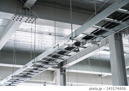 Industrial ceiling view featuring galvanized steel cable trays and structural support beams 143174808