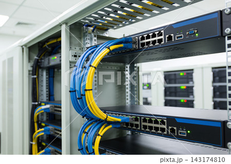 Network server rack with organized blue and yellow ethernet cables in a modern data center room 143174810
