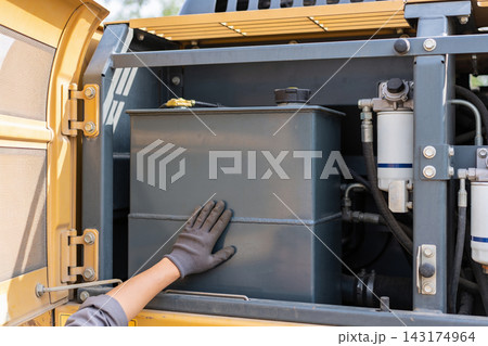Mechanic performing routine maintenance on a heavy construction excavator engine compartment Mechanic performing routine maintenance on a heavy construction excavator engine compartment 143174964