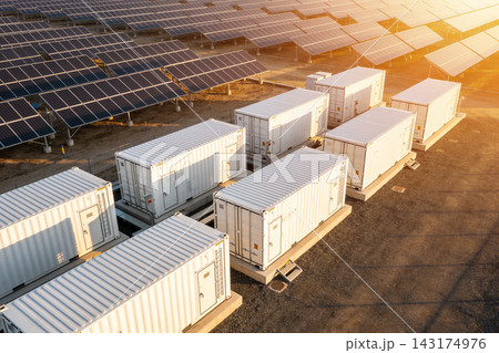 Aerial view of a large solar farm with energy storage containers at golden hour sunset light 143174976