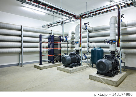 Industrial mechanical room featuring high-efficiency water pumps and heat exchanger equipment 143174990