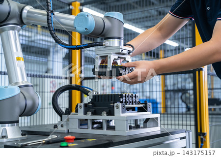 Industrial robotic arm assisting a technician with precise electronic component assembly tasks Industrial robotic arm assisting a technician with precise electronic component assembly tasks 143175157