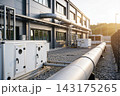 Industrial building exterior with large HVAC ventilation units and metal piping at sunset 143175265
