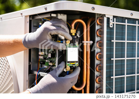 Technician hands installing a smart controller module into an outdoor air conditioning unit 143175270