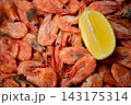 A close-up of frozen shrimps with a pronounced layer of frost, a bright slice of lemon is located on the right side of the frame. The concept: an emphasis on frost crystals, a contrast with the 143175314