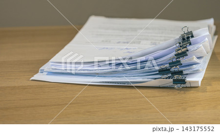 Stacked business documents secured with binder clips Stacked business documents secured with binder clips 143175552