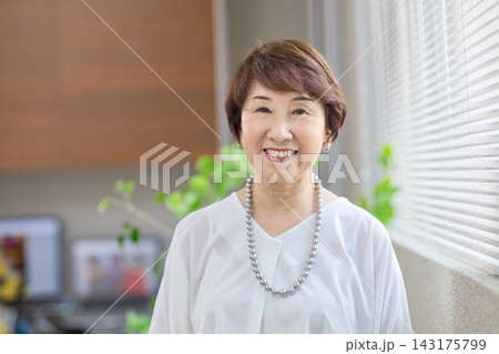オフィスの窓際で微笑む60代女性 143175799