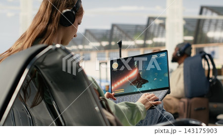 Excited gamer playing online competition game in airport terminal, strategy and interactive action while waiting plane. Modern travel moment with gaming as relaxation and entertainment. Excited gamer playing online competition game in airport terminal, strategy and interactive action while waiting plane. Modern travel moment with gaming as relaxation and entertainment. 143175903