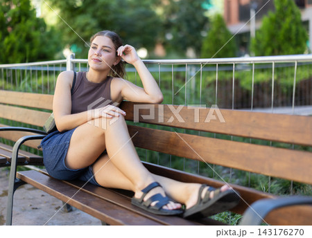 Girl is relaxing on bench in park Girl is relaxing on bench in park 143176270