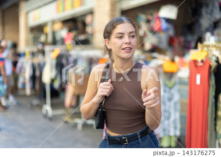 Young woman examining clothes at outdoor street market stall Young woman examining clothes at outdoor street market stall 143176275