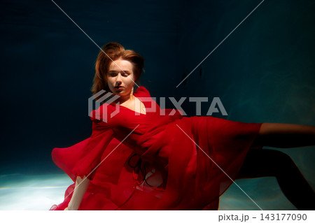 Caucasian woman underwater fashion seduction in red dress 143177090