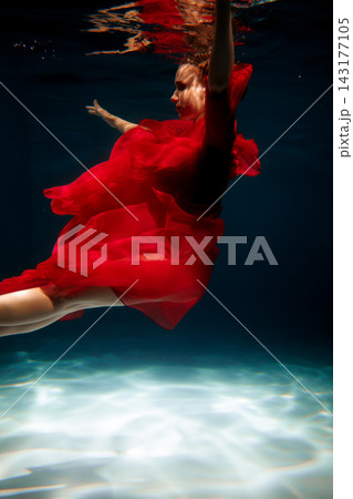 Hopeful woman rising. Woman in red reaches upward beneath water Hopeful woman rising. Woman in red reaches upward beneath water 143177105