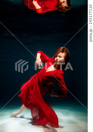 Underwater scene features poised dancer in flowing red costume Underwater scene features poised dancer in flowing red costume 143177110