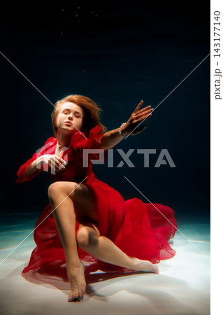 Caucasian model submerged wearing red dress, editorial Caucasian model submerged wearing red dress, editorial 143177140