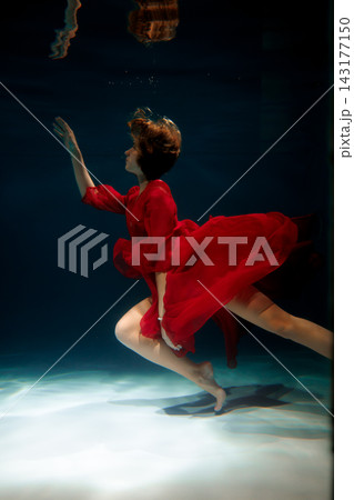 Urgent underwater runner in red dress, dramatic motion 143177150
