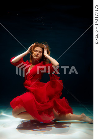 Red dressed model resembling lively aquatic sculpture beneath water surface 143177175