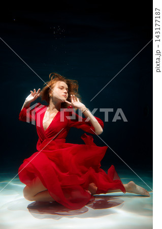 Underwater female figure in flowing red gown creating cinematic tension Underwater female figure in flowing red gown creating cinematic tension 143177187