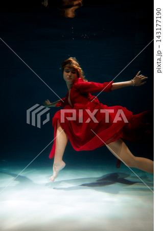 Confident underwater model in red dress taking theatrical stride Confident underwater model in red dress taking theatrical stride 143177190