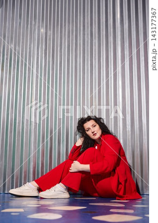 Serene female figure in vibrant attire standing near shiny wall Serene female figure in vibrant attire standing near shiny wall 143177367