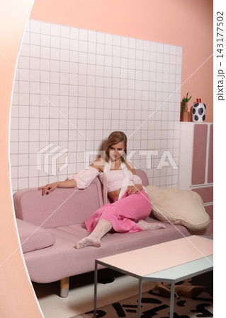 Chic individual photographs herself on sofa with warm lighting and decor 143177502