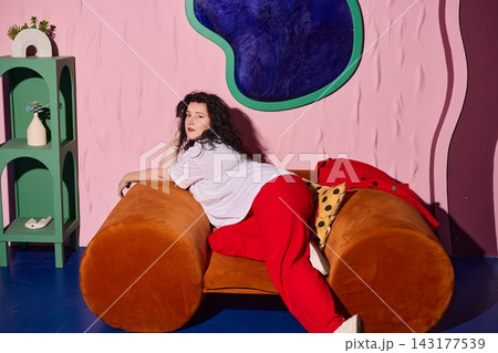 Relaxed female leaning against soft velvet cushions in warm toned space 143177539
