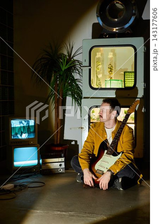 Male songwriter sitting beside vintage television and guitar Male songwriter sitting beside vintage television and guitar 143177606