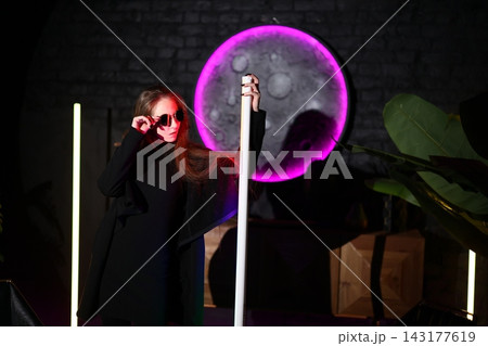 Secretive female participant dazzles beneath glowing neon illumination 143177619