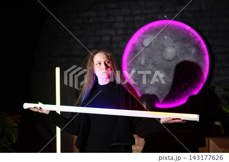 Elegant female presenter demonstrates glowing LED bar with neon background Elegant female presenter demonstrates glowing LED bar with neon background 143177626