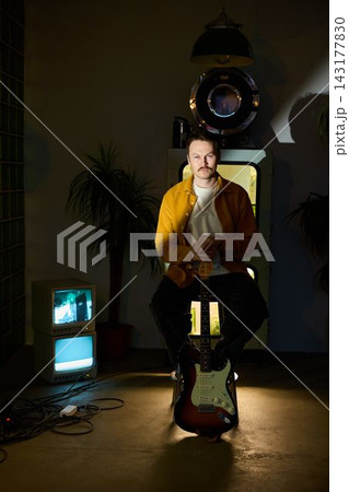 Promotional image of man playing electric guitar with retro elements Promotional image of man playing electric guitar with retro elements 143177830
