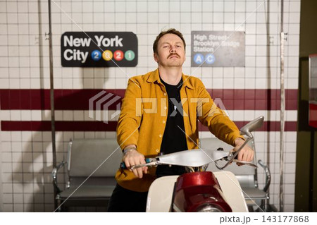 Urban scene featuring smiling man on scooter with warm lighting 143177868