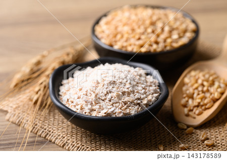 Whole wheat flour and dried wheat grain in a black bowl, food ingredient Whole wheat flour and dried wheat grain in a black bowl, food ingredient 143178589