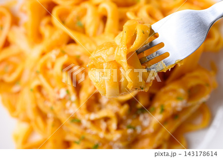 Eating butternut squash pasta topped with grated parmesan cheese and fresh herbs Eating butternut squash pasta topped with grated parmesan cheese and fresh herbs 143178614