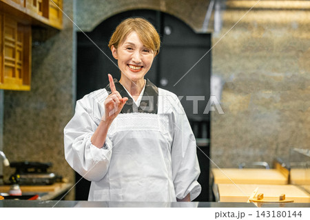 カウンターに立って料理をする女将 カウンターに立って料理をする女将 143180144