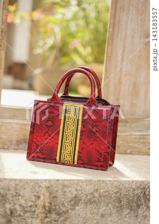 handmade red handbag with bold tassel accent, photographed outdoors in warm natural light to evoke craft, style and vintage inspired summer fashion. handmade red handbag with bold tassel accent, photographed outdoors in warm natural light to evoke craft, style and vintage inspired summer fashion. 143183557
