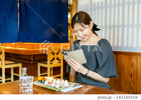 寿司屋で一人でランチに来てスマホで撮影をする若い女性 寿司屋で一人でランチに来てスマホで撮影をする若い女性 143185419