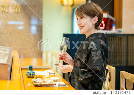 寿司屋のカウンターで大将と会話するシニア女性客 寿司屋のカウンターで大将と会話するシニア女性客 143185475