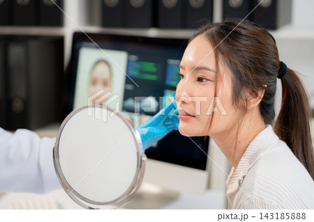 Asian woman patient looking in mirror with anxiety and checking skin face problem. 143185888