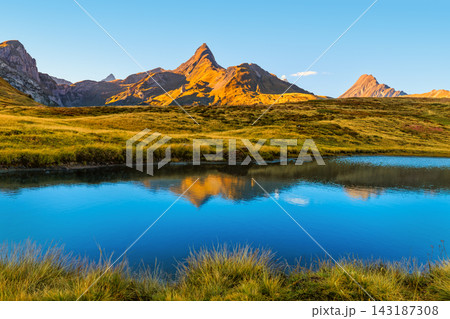 Alpine lake reflecting mountain peaks bathed in golden sunset light at Little St Bernard Pass, Italy Alpine lake reflecting mountain peaks bathed in golden sunset light at Little St Bernard Pass, Italy 143187308