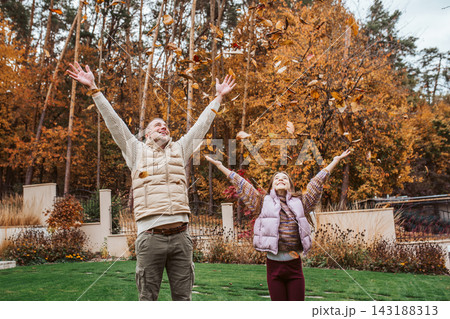 Father playing with daughter, throwing autumn leaves in the air. 143188313