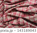 A wrinkled and folded fabric with a pink and white plaid pattern 143189043