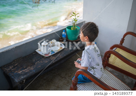 Young boy gazing at ocean view from balcony in Sri Lanka Young boy gazing at ocean view from balcony in Sri Lanka 143189377