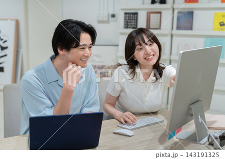 パソコンの画面を見ながら話す若い男女 クリエイティブチームの仕事風景 パソコンの画面を見ながら話す若い男女 クリエイティブチームの仕事風景 143191325