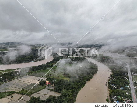 Heavy clouds and continuous drizzle blanket winding Sakae Krang and Chao Phraya river confluence amidst mist covered rural landscape. Heavy clouds and continuous drizzle blanket winding Sakae Krang and Chao Phraya river confluence amidst mist covered rural landscape. 143191650