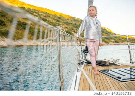 Young girl walking barefoot on sailing yacht deck near Croatian coast. Sailing vacation gives children freedom, confidence and experience of life at sea Young girl walking barefoot on sailing yacht deck near Croatian coast. Sailing vacation gives children freedom, confidence and experience of life at sea 143191732