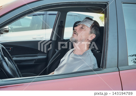 Man feeling unwell inside parked car, experiencing illness or heat exhaustion Man feeling unwell inside parked car, experiencing illness or heat exhaustion 143194789