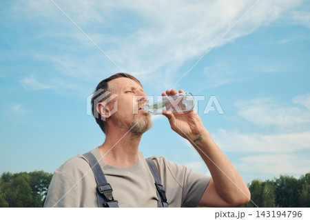 Man hydrating and quenching thirst under blue sky on warm day 143194796