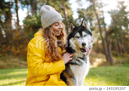 Young woman walks with her husky on lawn in the park. Happy female posing outdoors with her dog. Young woman walks with her husky on lawn in the park. Happy female posing outdoors with her dog. 143195207