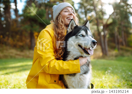 Young woman walks with her husky on lawn in the park. Happy female posing outdoors with her dog. Young woman walks with her husky on lawn in the park. Happy female posing outdoors with her dog. 143195214